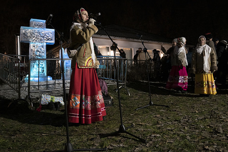 A woman dressed in a traditional costume sings during the celebration.
The annual commemoration of the baptism of Jesus Christ in the Jordan River is celebrated by thousands of Russian Orthodox believers as part of celebrations for the Epiphany fest. Despite the unusual warm temperature that hampered the formation of a strong ice cover of lakes and rivers, several stations had been prepared in the urban area in Moscow, as the one in the Sokolniki Park, for believers who wanted to take the traditional plunge that is considered an act for washing out one’s sins.