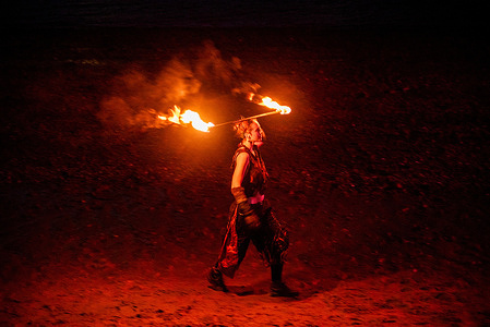 A female juggler balances a burning stick on her head during the show. Members of London Fire Spinners gathered on the south bank of the River Thames in the night for their annual juggling event.