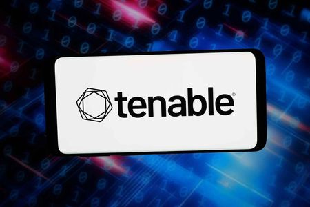 In this photo illustration, the cybersecurity company Tenable Holdings Inc. logo is seen displayed on a smartphone in front of abstract background on computer screen.