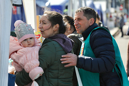 A volunteer guides a mother and her child who just arrived in front of a humanitarian tent in Siret after crossing the Ukraine border. Siret, a small border town in northern Romania with 8,000 residents, lies 500 kilometers from Kyiv, Ukraine. Since Russia's invasion of Ukraine on February 24, 2022, thousands of Ukrainian refugees have passed through daily. By April 2022, some Ukrainians began making the reverse journey, returning home after weeks of refuge in Romania.