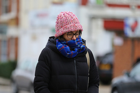 A woman using a scarf as a face mask walks on the street.