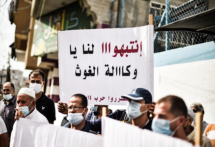 Protesters holding placards expressing heir opinion, during the demonstration.
Palestinians protest at the United Nations Relief and Works Agency for Palestine Refugees (UNRWA) in Khan Yunis demanding rebuilding of homes destroyed during the 2014 Israeli war.