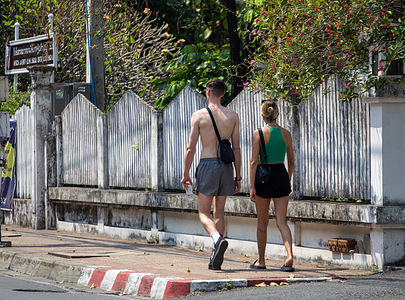 A shirtless tourist moves near Tha Phae Gate on a hot and sunny day. The “very” hot weather was caused by a warm low pressure over upper Thailand, and it will continue for a while.