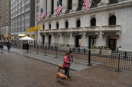 A person walks a dog past the New York Stock Exchange in the Financial District in Manhattan, New York City.