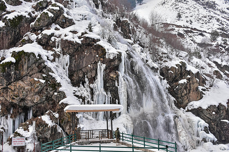 A paramilitary trooper keep vigil at the partially frozen Drang waterfall, after heavy snowfall during a winter day in Drang, about 45kms from Srinagar, the summer capital of Jammu and Kashmir.