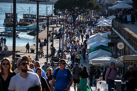 Crowds of people are walking along the banks of the Douro river in the historical area of Porto.