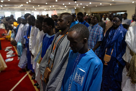 Several men pray during the festival. The Grand Magal of Touba is the most important religious festival of the Mourid Brotherhood in Senegal, a branch of Sufi Islam. It is celebrated annually in the city of Touba to commemorate the life and teachings of its founder, Cheikh Ahmadou Bamba.
