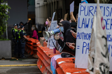 A pro-trans rights group protester uses a megaphone to heckle police. In Melbourne, Trans Rights groups organized a counter-rally in response to an anti-trans event held at the state parliament. The demonstration, aimed at promoting equality and standing against discrimination, concluded with a march through the city center, drawing significant support from activists and allies across the community.