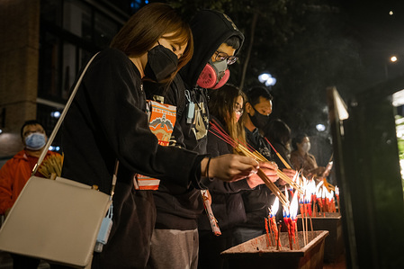 A couple with protective face masks as a protective measure from the Coronavirus while light up their incenses before entering the Kwun Yum temple during the Kwun Yum Treasury festival.
Despite the risk of spreading the Cornavirus, thousands of believers headed to the Kwun Yum temple to pray and ask to "borrow" money from the goddess of mercy Kwun Yum on the night of the Kwun Yam Treasury Festival. In order to control the risk of spreading the Cornavirus the temple authority only allow people wearing face masks to enter the temple.