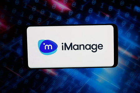 In this photo illustration, the logo of US software company iManage LLC is displayed on a smartphone in front of abstract background on computer screen.
