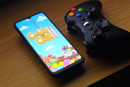 In this photo illustration, the Candy Crush Saga logo is seen displayed on a smartphone screen next to an Xbox video game controller.