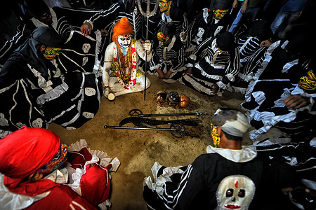 Hindu devotees seen seated with human skull during the night ritual of Gajan festival . Gajan associated with gods as Shiva, Neel and Dharmathakur. It is spans around a week, starting at the last week of Choitro continuing till the end of the Bengali year. Participants of this festival are known as sannyasi or Bhokta. The central theme of this festival is deriving satisfaction through non-sexual pain, devotion and sacrifice.