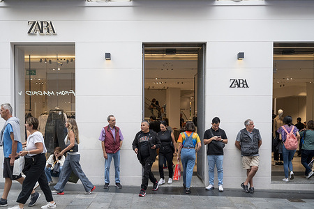 Pedestrians and shoppers are seen in front of the Spanish multinational clothing design retail company by Inditex, Zara, a store in Spain.