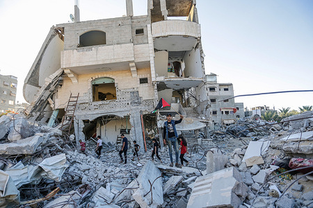 Palestinians stand with their national flags at a building destroyed by Israeli air strikes, during a demonstration against the controversial flag march, organized by some 5,000 right-wing Israeli citizens through the Old City of Jerusalem.