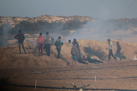 Palestinian demonstrators seen taking cover from teargas during clashes along the border between Israel and the Gaza Strip near Beit Lahia in the northern Gaza Strip after a protest by Palestinians demanding to return to their homes from which they were expelled during the 1948 war.