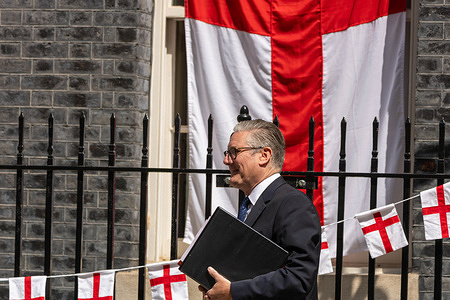 Keir Starmer, Prime Minister, walks past St George's flag bunting hung in Downing Street for the England World Cup match as he leaves for his last Prime Minister's Questions.