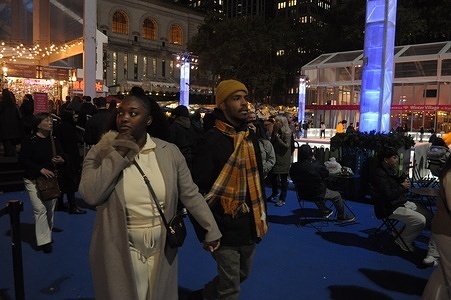People walk in Bryant Park Winter Village, a seasonal holiday-themed venue full of vendors and an ice skating rink, in Manhattan, New York City.