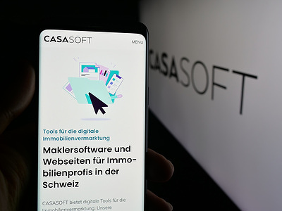 In this photo illustration, a person is holding a smartphone with the webpage of Swiss property software company Casasoft AG on screen in front of logo.