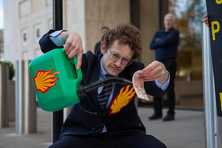 A Fossil Free activist pours red liquid over fake money during a demonstration outside Shell headquarters. Campaign group Fossil Free London held a protest outside Shell’s headquarters in central London on 6th May 2026, just before the company announced its quarterly profits. Two activists stood beside a mock fossil fuel pump marked “Oil Profit$$$ for Oil Boss$$es,” while others, dressed as corporate executives, poured red liquid—symbolising blood—over a further two activists dressed in white. The demonstrators also carried fake money, and banners which read: “Shell Profits Blood Money.”