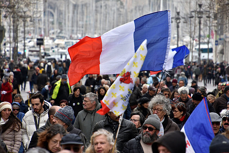 A protester holds a flag in the middle of the crowd during the demonstration. Protesters took to the streets of Marseille to protest against draconian measures such as the vaccination pass imposed by the French government.