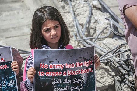 A Palestinian student holds a placard on the rubble of her destroyed aqaba mixed basic school protesting against its demolition by Israeli forces in the village of Aqaba in the northern Jordan Valley, north of the occupied West Bank.