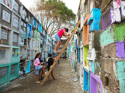 A woman comes down from a wooden ladder after putting flowers on her deceased relative's tomb. Filipinos flock to different cemeteries to observe UNDAS or All Saints Day in different parts of the Philippines. Offering flowers and candles to be placed at the graves of their deceased relatives.