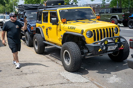 A man walks in front of Jeeps parked outside Offroad Fab Shop NY during a community barbecue and fundraiser benefiting earthquake recovery efforts in Venezuela event, where owners and enthusiasts gathered to share food, showcase their vehicles and connect with fellow off-road enthusiasts on June 28, 2026 in the Queens borough of New York City. The event brought together Jeep owners from across the region for an afternoon of fellowship, vehicle displays and community engagement.