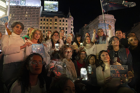 A group of protesters pose for a photo holding lights, placards, and jars filled with wáter during the rally. Protesters marched with torches through downtown Buenos Aires to protest against the reform of the Glacier Protection Law, which the ruling party seeks to pass. The reform will be discussed in Congress for final approval on Wednesday, 15. Environmental organizations, scientific collectives, and political groups mobilized under the slogan “the law is not to be touched”.