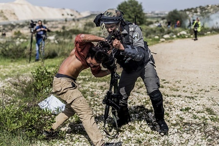 Israeli border policeman seen arresting an international activist during the protest.
Palestinians protested to commemorate the thirteenth anniversary of the construction of the wall that separates Palestinian territory from land that was taken by the Israeli army and where settlers now reside.