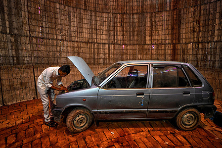 A mechanic seen preparing a car for the Stunt show inside the Well of Death, locally known as Maut ka kuaan at a Mela (Fair) ground. This well or bowl - also known as a wall of death, is about 30 feet deep and made from wooden planks, supported from the outside.
