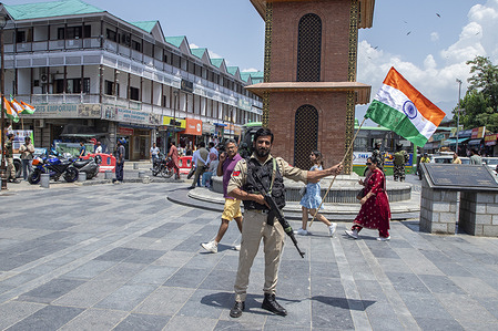 Indian policeman holds an Indian national flag as supporters of the Bharatiya Janata Party (BJP) celebrate the sixth anniversary of the abrogation of Article 370 and Jammu and Kashmir's special status at the City Center Lal Chowk. Indian Prime Minister Narendra Modi's government repealed Article 370 on 5th August 2019, ending the region's statehood special semi-autonomous status.