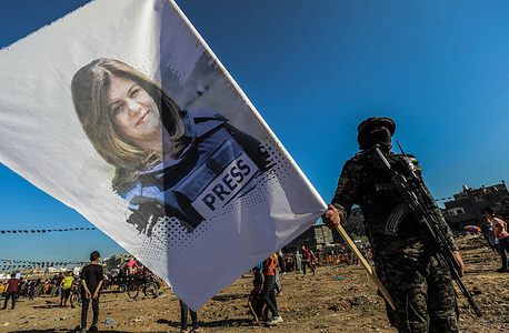 A Palestinian fighter from Saraya al-Quds, the military wing of the Islamic Jihad movement in Palestine, holds a banner with a picture of Shireen Abu Akleh at a demonstration commemorating the rally marking the first anniversary of the conflict between Israel and Gaza in Beit Hanun, northern Gaza Strip.