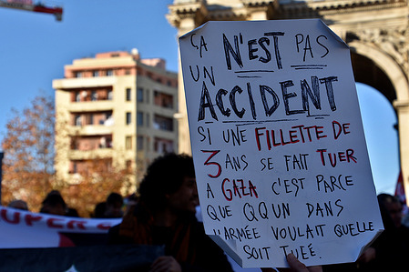 A Palestinian protester holds a placard with inscriptions “this is not an accident” and “if a 3 year old girl is killed in Gaza it is because someone in the army wanted her to be killed” during the demonstration against the war in Palestine.