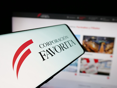 In this photo illustration, a smartphone with the logo of retail company Corporacion Favorita C.A. is seen on screen in front of website.