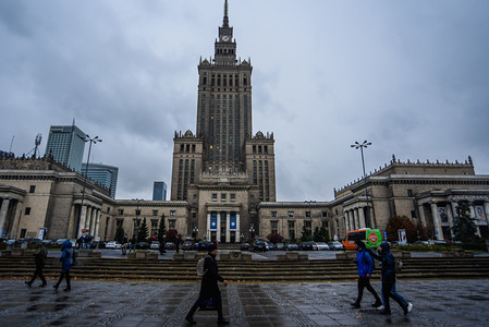 People pass by the Palace of Culture and Science in Warsaw during a rainy day.
