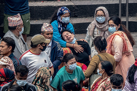 A woman cries as relatives carry Kush grass effigies representing missing flood victims during symbolic Hindu cremation rites at Pashupatinath Temple in Kathmandu. Families held the ceremonies to honor and liberate the souls of loved ones lost after deadly flash floods devastated villages in the region a week prior.