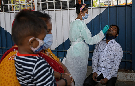 A healthcare worker wearing a personal protective equipment suit (PPE) collects a nasal swab from a man on arrival at Dadar Terminus.
Passengers arriving in trains to Mumbai from the state of Gujarat are screened for oxygen level, temperature and if found to be suffering from fever have to undergo swab tests at the railway station before being allowed to proceed to their respective destination.