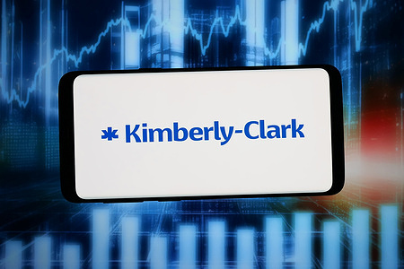 In this photo illustration, the logo of US company Kimberly-Clark Corporation is displayed on a smartphone in front of abstract background on computer screen.