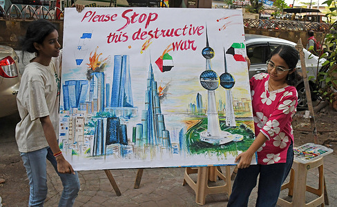 Students from Gurukul school of art carry back a poster with a message 'stop this destructive war' with Iran outside their art school in Mumbai.