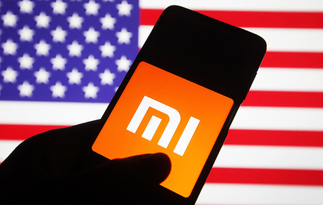 In this photo illustration, Xiaomi logo is seen on a Xiaomi mobile phone screen in front of the flag of the US. The administration of US President Donald Trump added Chinese companies including Chinese electronics company Xiaomi to a blacklist, which will be subject to a new US investment ban, reportedly by media.