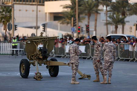 Qatari police officers prepare to fire a cannon to announce the time for breaking the fast on the first day of the holy month of Ramadan in Souq Waqif.