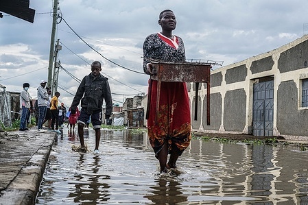 A woman wades through carries her cooking stove as she wades through a flooded street in Kihoto, a low-income community severely affected by the rising waters of Lake Naivasha. Hundreds of residents continue to evacuate from their flooded homes as Lake Naivasha, about 90 km northwest of Nairobi, reaches unprecedented levels. The lake has been expanding since 2020, with conditions worsening this year due to prolonged rainfall. Other Rift Valley lakes have also been steadily rising, intensifying the regional flooding crisis.