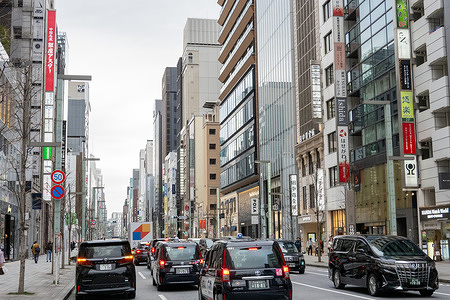 Taxis and pedestrians move through a busy street in the Ginza district of Tokyo, Japan. The upscale commercial area is known for its wide avenues, department stores, and modern office buildings. Ginza is Tokyo’s upscale shopping district, known for its luxury boutiques, department stores, and refined dining scene. Its wide, polished streets and modern architecture make it one of the city’s most sophisticated and high-end areas.