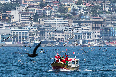 Santa Claus and his helpers seen sailing along the city's coast to greet children during a Christmas festival. In Valparaíso, Chile, artisanal fishermen celebrate Christmas with Santa Claus on a boat in the port's bay, concluding the event by distributing gifts to children.