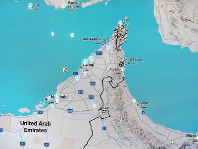 A live map from flightradar24.com shows air traffic activity over the United Arab Emirates, with a yellow airplane icon approaching the Dubai coastline. The surrounding Gulf airspace appears relatively calm compared to neighboring regions, highlighting the contrast between concentrated traffic corridors and restricted or avoided zones nearby.