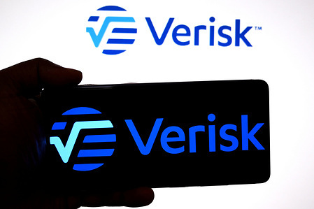 In this photo illustration, a Verisk logo is seen displayed on a smartphone and in the background.