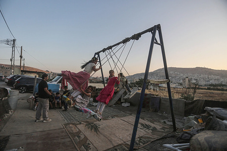 Palestinian children enjoy traditional games at Askar refugee camp during Eid al-Adha. Muslims celebrate the first three days of Eid al-Adha. Eid al-Adha commemorates the willingness of the Prophet Abraham (Ibrahim to Christians and Jews) to sacrifice his son. During the approximately four-day holiday, Muslims slaughter sheep or cattle, distribute part of the meat to the poor, eat the rest, and wear new clothes.