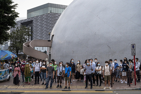 Pedestrians wearing face masks wait at a traffic light next to the Space museum in Hong Kong.