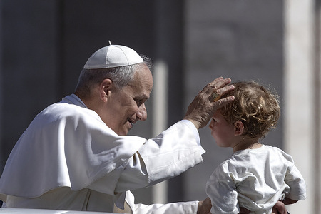 Pope Leo XIV greets a child upon his arrival in his popemobile before celebrating Mass for the Jubilee of Families, Children, Grandparents, and the Elderly in St. Peter's Square at the Vatican.