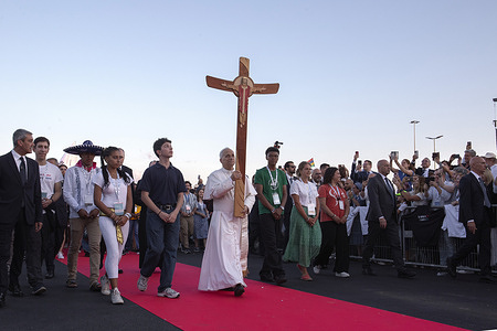 Pope Leo XIV holds the cross as he arrives in Tor Vergata, on the outskirts of Rome, to lead the prayer vigil on the occasion of the Jubilee of Youth.